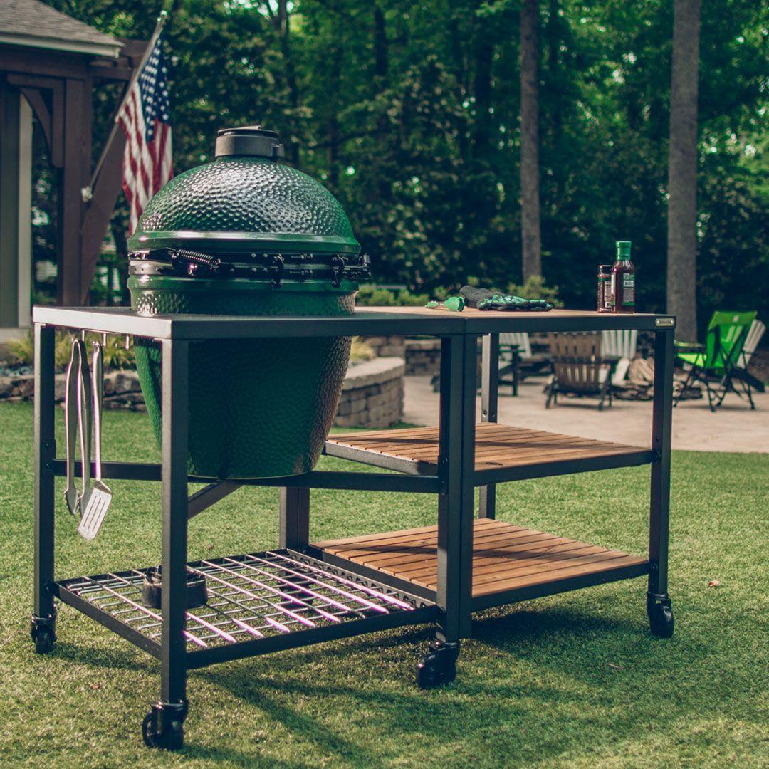 Big Green Egg set into a wood and steel table in a backyard